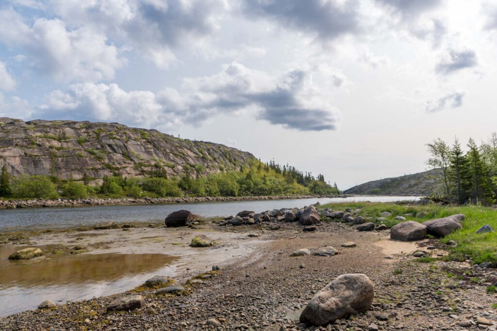 Панорама архипелага Кузова на Соловках, светлая отмель, крупные камни и скалистый склон под облаками
