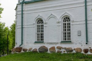 Стена храма Вознесения на Секирной горе с высокими окнами и каменным цоколем