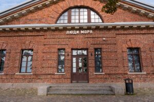 Люди моря в Кронштадте у кирпичного здания и набережной