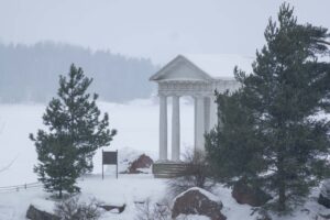 Белые колонны Храма Нептуна Монрепо среди сосен и валунов
