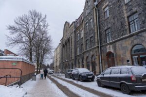 Гранитный дворец Хакманов с арочными входами за заснеженными машинами