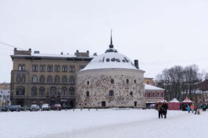 Круглая башня Выборга за снежной площадью с посетителями