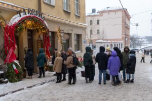 Посетители у входа в Таверну с красными лентами зимой