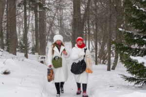 Две посетительницы в белых пальто на снежной дорожке