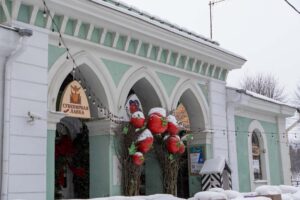 Зелёный фасад выборгской гауптвахты с сувенирной лавкой и красными украшениями