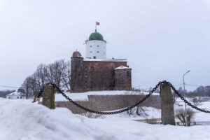 Выборгский замок за цепями ограждения и снежными сугробами